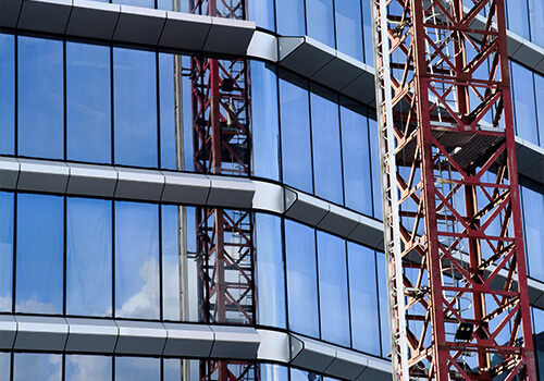 Crane in front of a glass and concrete building