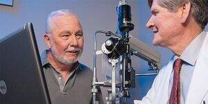 A man sits and consults with his ophthalmologist discussing his eye health.
