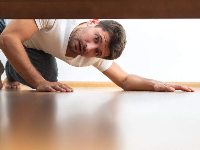 man looking under the bed 