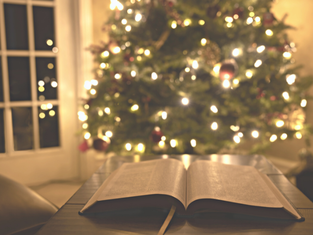 lit Christmas tree and an open Bible