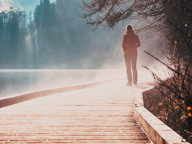 woman walking next to a lake on a foggy day
