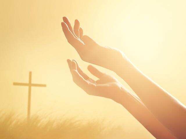 hands raised toward almighty God and a cross in the background