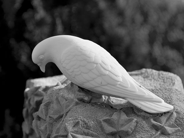 a white dove sculptured on top of a tombstone