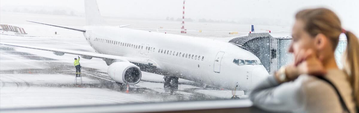 woman with canceled flight looks at plane stuck on runway in snow