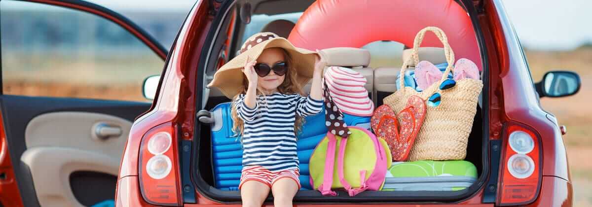girl sitting in trunk of car after using travel packing tips