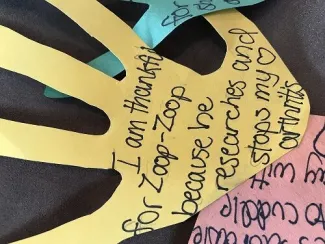Yellow, blue and pink construction paper hands that have thank you notes written on them in black sharpie ink.