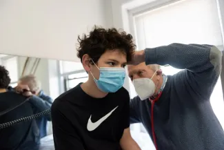 a young boy wearing a mask getting his ear examined