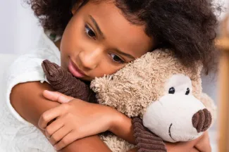 Concerned girl holds stuffed animal