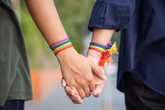 Teens wearing rainbow bracelets hold hands