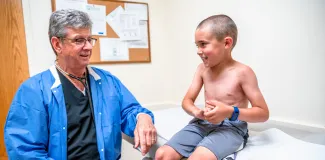 a young boy and a pediatrician looking at each other smiling