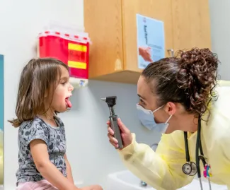 young girl getting her tonsils examined by a doctor