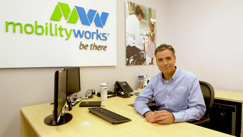 hombre en camisa MobilityWorks sentado en un escritorio