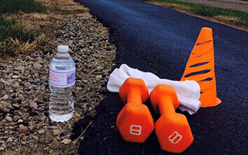 A water bottle, orange 8 pound weights, a towel and an orange cone on the 1.1 mile track at Keller Logistics Group as part of the employee wellness program