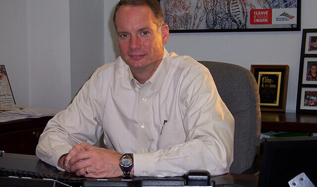 Bryan Keller sitting at his new desk as CEO in 2000