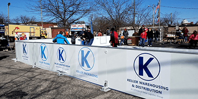 Keller Logistics Group and affiliates logos along the side of a skating rink for sponsoring a community event
