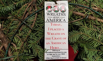 Wreath with a Wreaths Across America tag on it that says, "Today, I placed a wreath on the grave of an American Hero" part of Keller Logistics Group's National Community Service