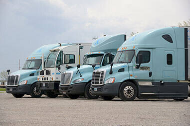 Four types of Keller Trucking semi tractors lined up which include a day cab, sleeper, and a spotter truck