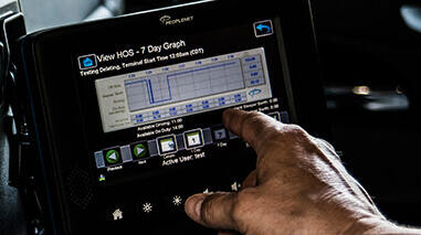 Peoplenet device in semi truck with a drivers hand reviewing the data on a touch screen 
