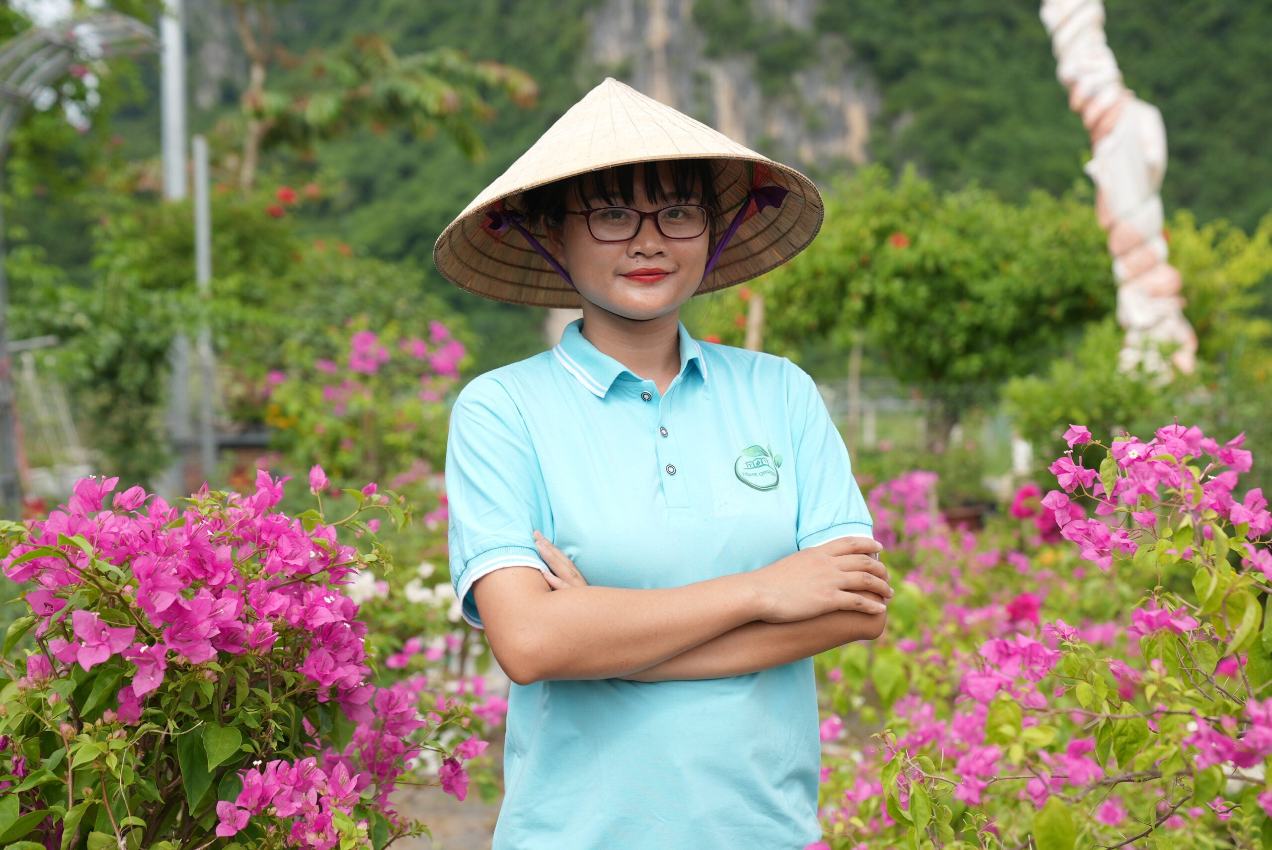 Pham Phuong Thao arms crossed to camera standing among flower bushes