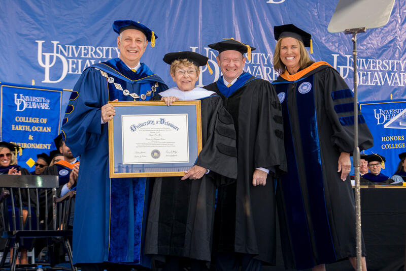  An honorary doctor of humane letters degree is presented to philanthropist and UD alumna Sally Ives Gore, mother of Delaware U.S. Sen. Chris Coons. Pictured are UD President Dennis Assanis, Ives Gore, Coons and Board Chair Terri L. Kelly.