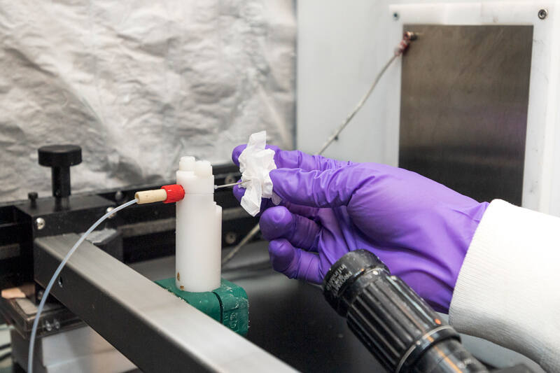 Eduardo Nombera-Bueno cleans the needle tip of an electrospinning machine, as part of his work experimenting with plant-based alternatives to petroleum-derived plastics.