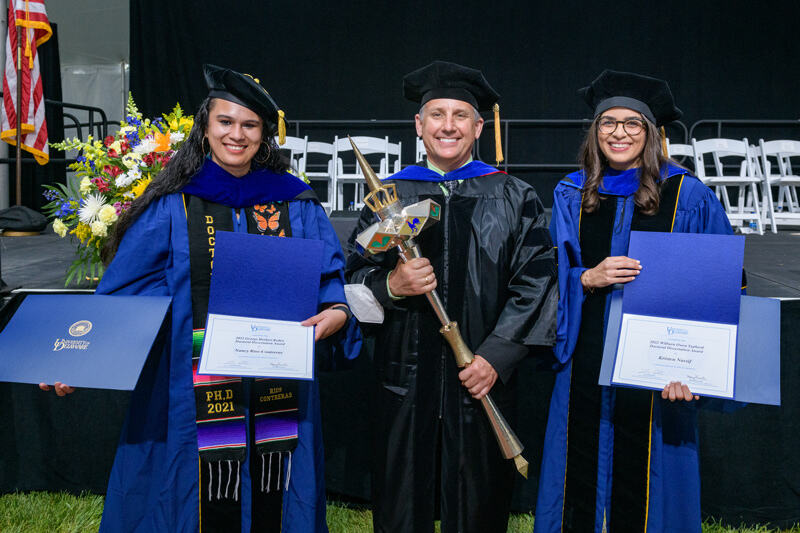 Six dissertation prizes were announced at the University of Delaware’s 2022 Doctoral Hooding Ceremony on Thursday, May 26. Two of the prize winners are in this photo. From left they are: Nancy Rios-Contrera, criminology, who won the George Herbert Ryden Prize in the Social Sciences; Lou Rossi, Dean of the Graduate College and Vice Provost for Graduate and Professional Education; and Kristen Nassif, art history, who won the Wilburn Owen Sypherd Prize in Humanities.