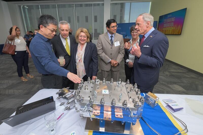 Professor Yushan Yan (left) provides an overview of the clean hydrogen electrolyzer technology discovered at UD and scaled up at Versogen, his startup company, to UD President Dennis Assanis, First Lady Eleni Assanis and U.S. Sen. Tom Carper. Versogen Chief Technology Officer Balsu Lakshmanan and Director of Membrane Production Sharon Perl are shown in the background. 
