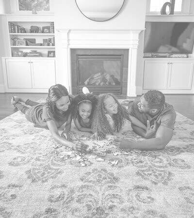Family laying on a clean area rug in the middle of their living room. 