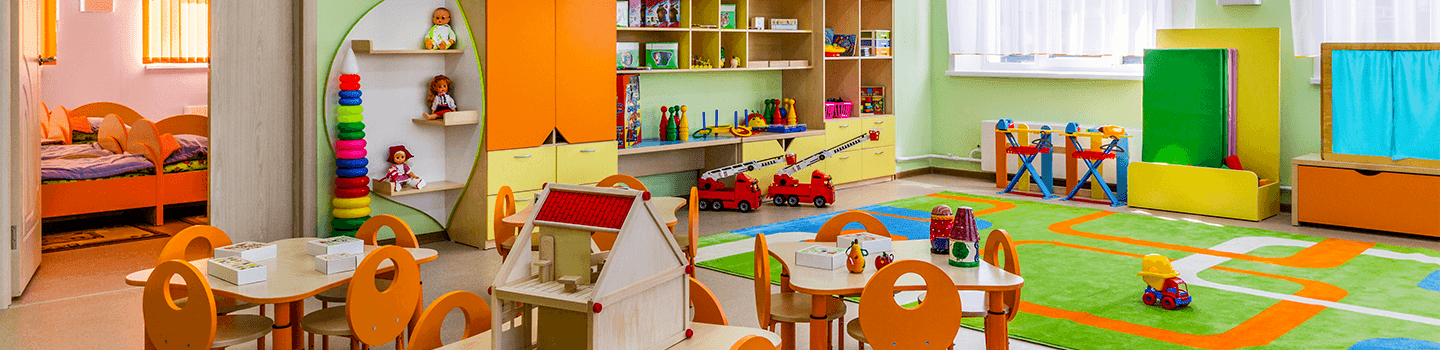 Daycare room with colorful toys, carpet, tables, and beds