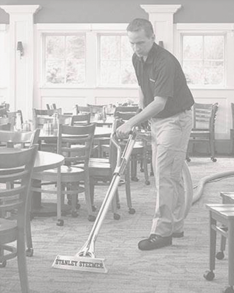 Stanley Steemer technician cleaning carpet in dining area of restaurant