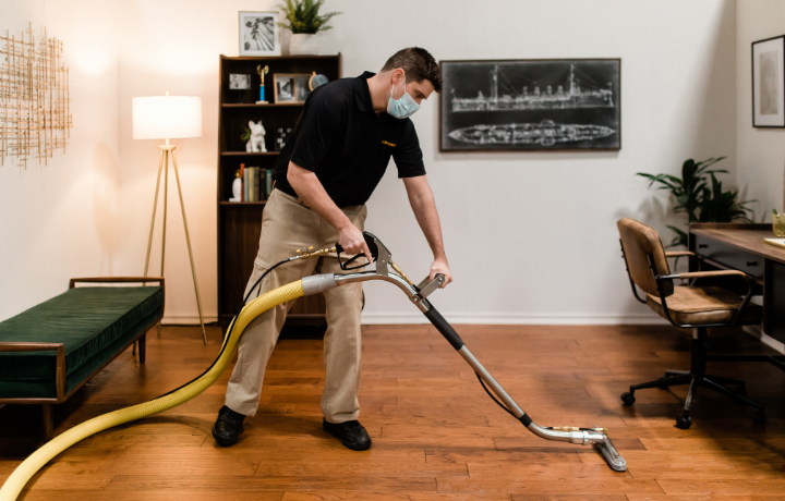 Technician professionally cleaning hardwood in new home
