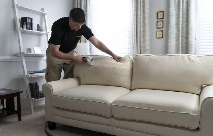 Technician cleaning couch before moving out of home