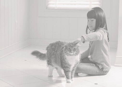 Girl sitting on a tile floor with her cat. 