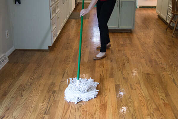 Woman mopping and cleaning hardwood floor in kitchen