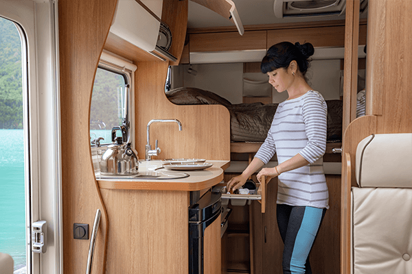 Woman opening a drawer in a small RV kitchenette