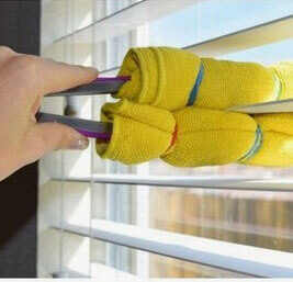 Hand cleaning blinds with a towel wrapped around kitchen tongs. 