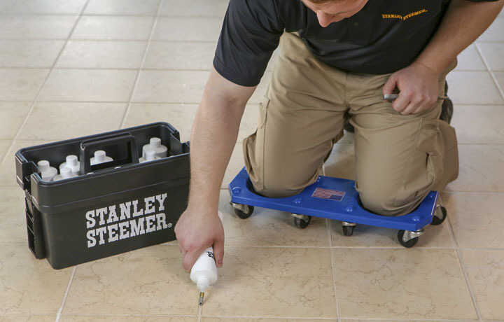 Stanley Steemer technician sealing the grout lines on a tile floor. 
