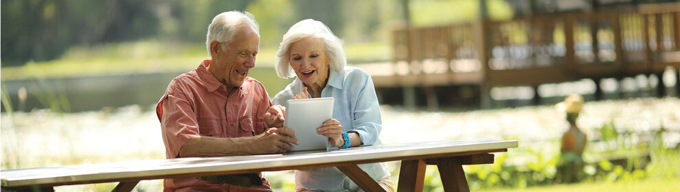 couple reviewing electronic banking on their laptop while sitting on a picnic table