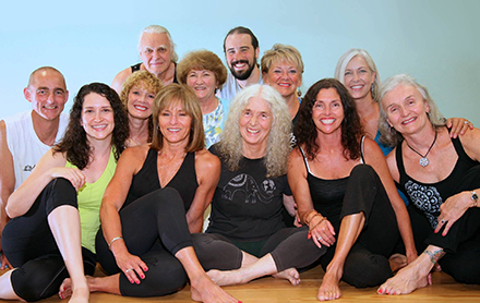 A group of yogis smiling together for a group photo after a yoga session.