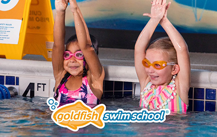 Two children swimming in the pool with Gold Fish Swim School.