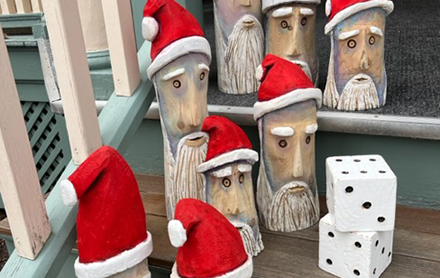Wood-carved Santa Claus decorations sold by The Village Gallery.
