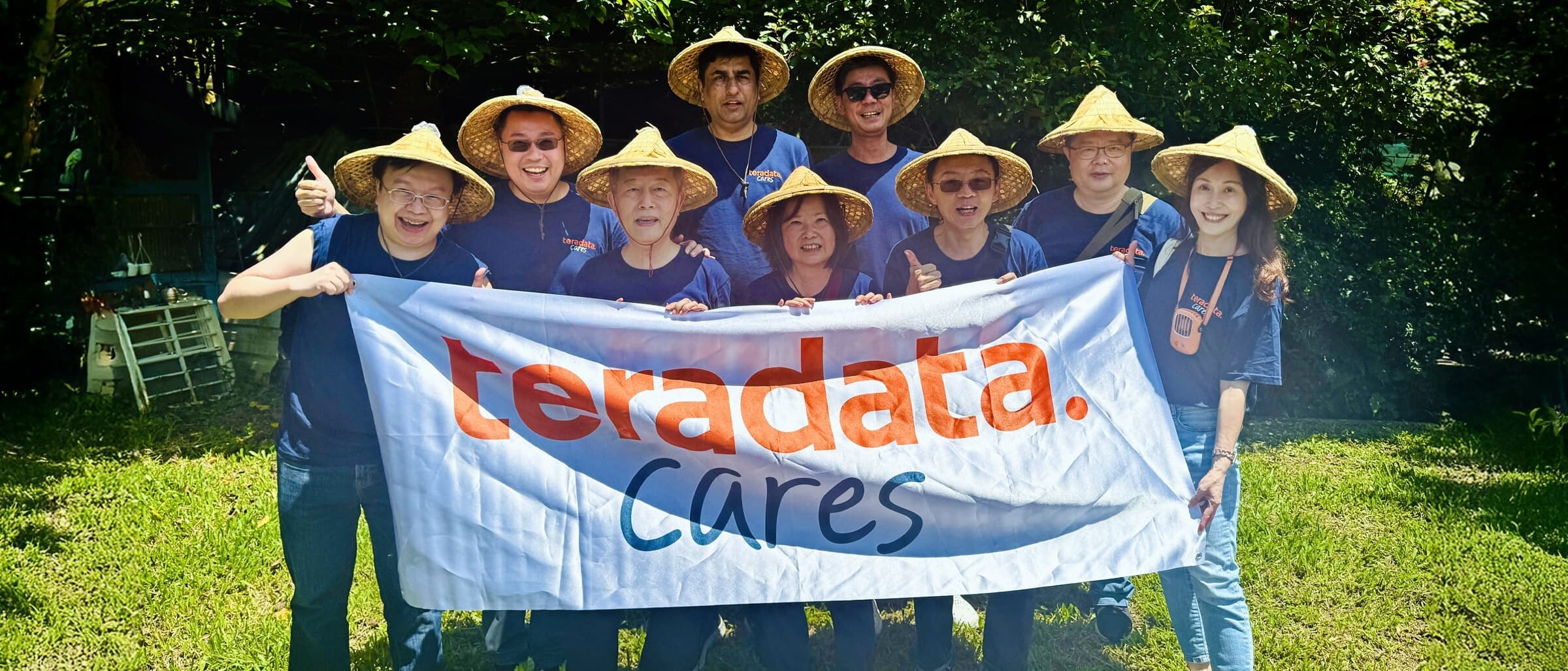 A group of people holding a Teradata cares banner.