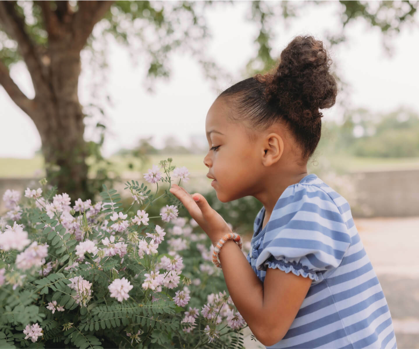 A young girl joyfully smelling flowers in a park