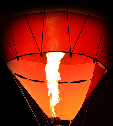 An orange hot air balloon with flame shooting up