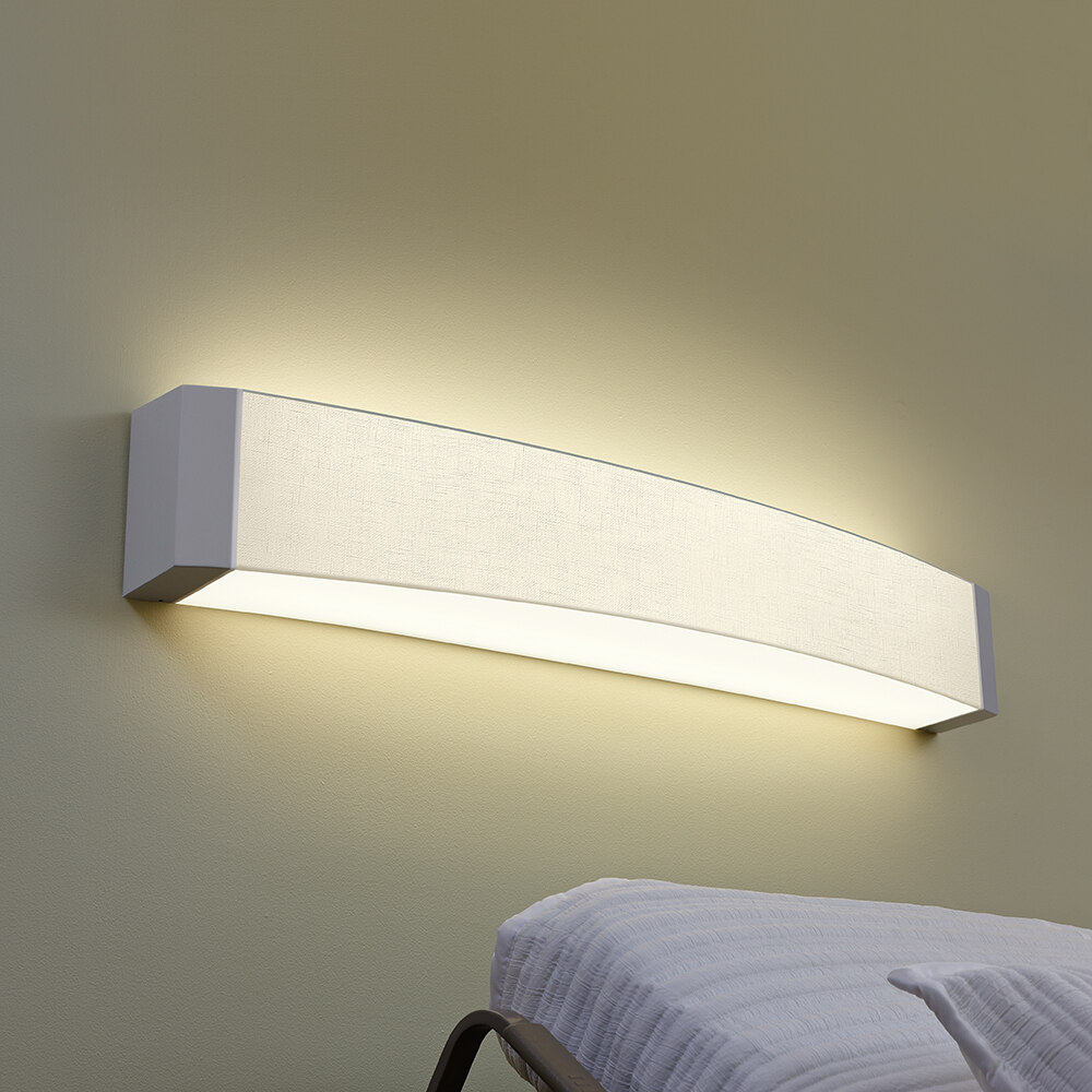 A curved linear headwall luminaire behind a patient bed