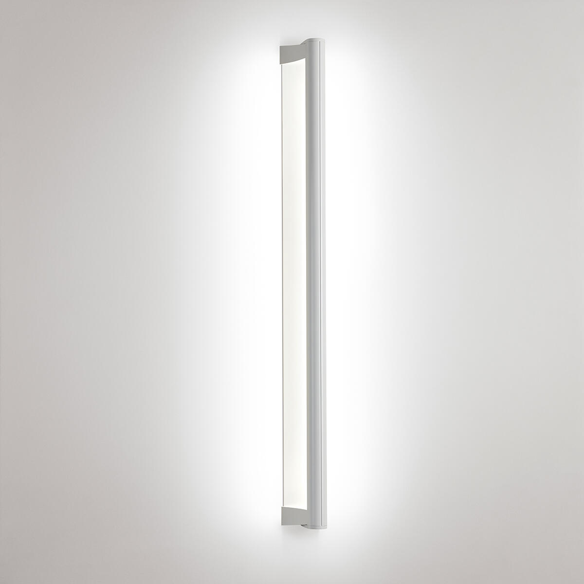 A surface mounted linear luminaire with a body that curves into the base with hidden indirect lighting