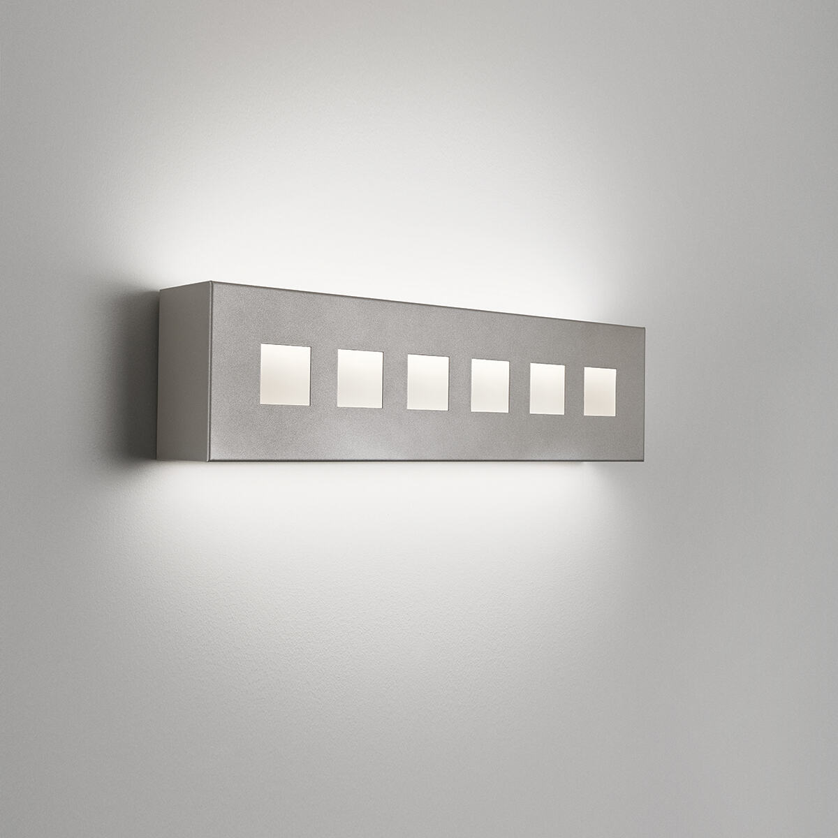 A box-like linear wall sonce with uplight and downlight with decorative windows