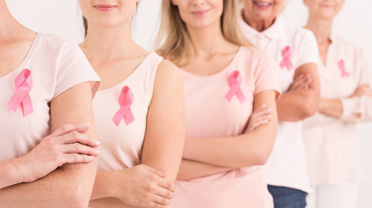 A line of women wearing pink shirts also wear pink ribbons to promote breast cancer awareness.