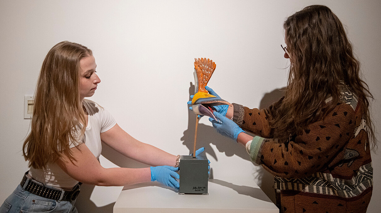 Greta Koshenina (right) works with student intern Sydney Lynch to install a piece in a new exhibit at the University Museum. Photo by Srijita Chattopadhyay/Ole Miss Digital Imaging Services