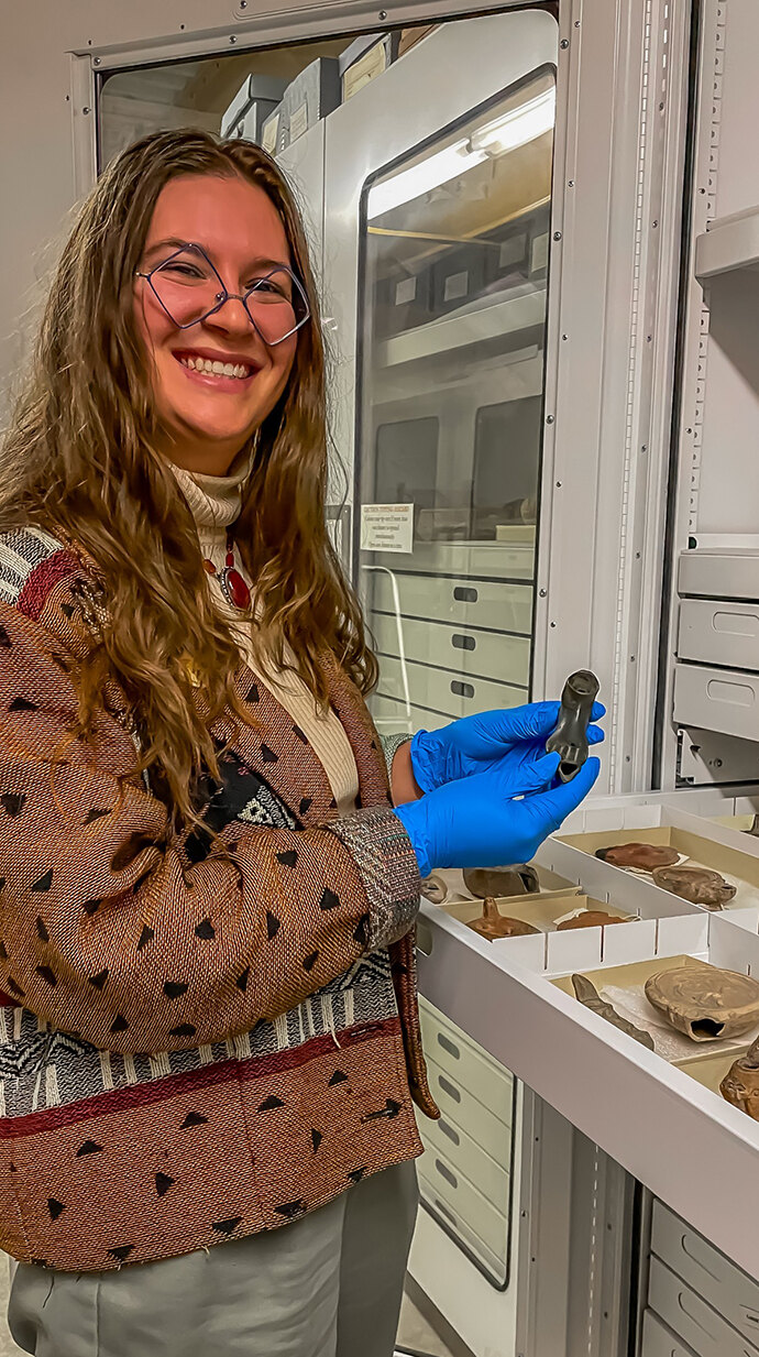Greta Koshenina examines artifacts in the University Museum's archive area. Photo by Peter Muvunyi